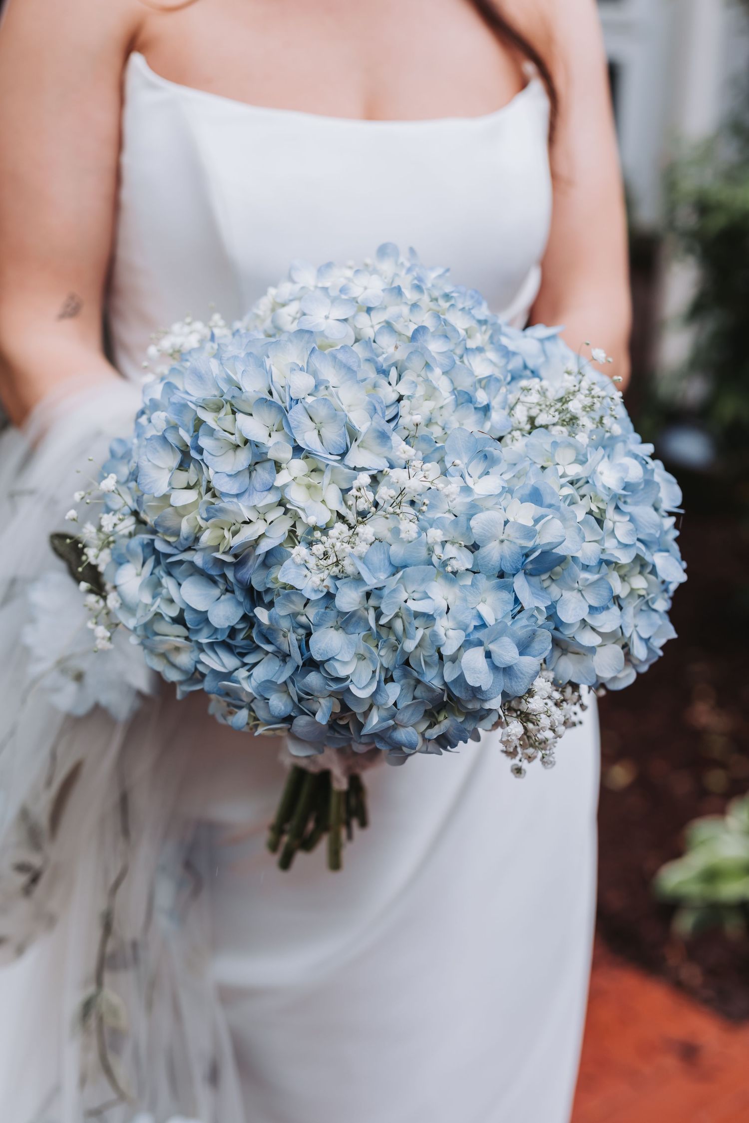 Close-up of a bridal bouquet of light blue hydrangeas and white baby's breath flowers.