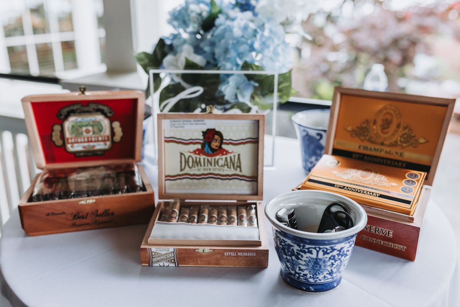 Three decorative cigar boxes displayed on white table at wedding reception cigar bar setup.
