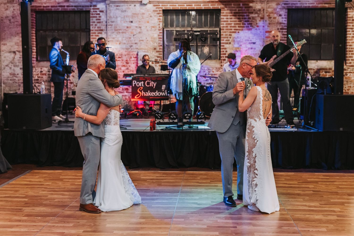 Two couples sharing parent dances in front of Port City Shakedown band at wedding reception.