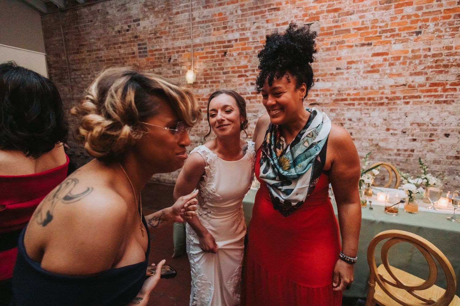 Bride in white gown laughing and celebrating with guests in colorful attire at wedding reception.