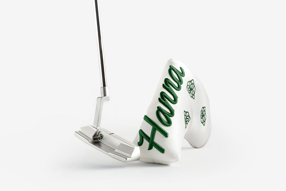 Custom silver golf putter with white head cover featuring green embroidered Hanna script lettering.