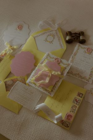 Yellow and pink wedding invitation suite with ribbon, wax seal, and decorative cards spread on white surface.