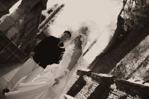 Black and white photo of a bride and groom standing together outdoors on their wedding day.