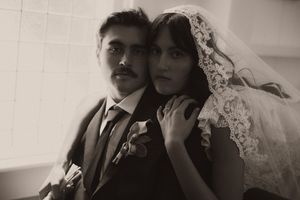 Black and white vintage wedding portrait of bride in lace veil and groom in suit with boutonniere.