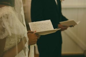 Bride and groom exchanging handwritten wedding vows during an intimate ceremony.