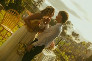 A couple shares a romantic dance outdoors at golden hour during their wedding celebration.