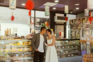Couple sharing a romantic moment in a Chinese bakery, woman in white dress, decorated with red lanterns.