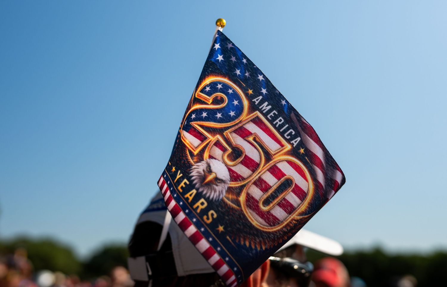 America 250 years anniversary flag with bald eagle design held at outdoor patriotic celebration event.