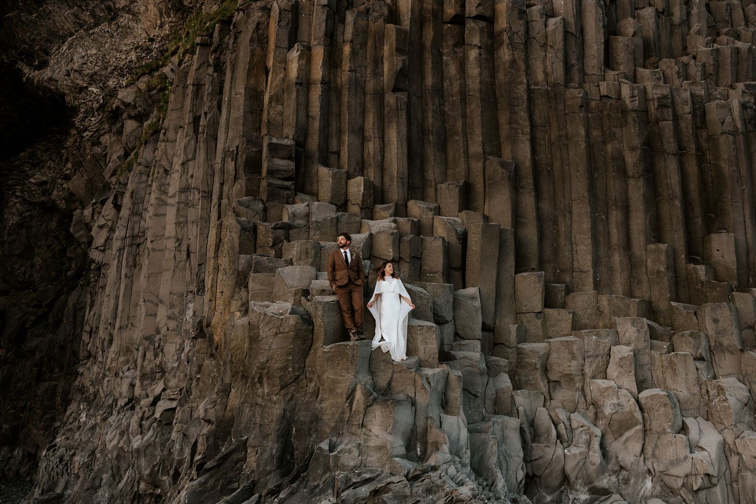 bride and groom standing on basalt columns at Reynisfjara Beach on their elopement day in Iceland
