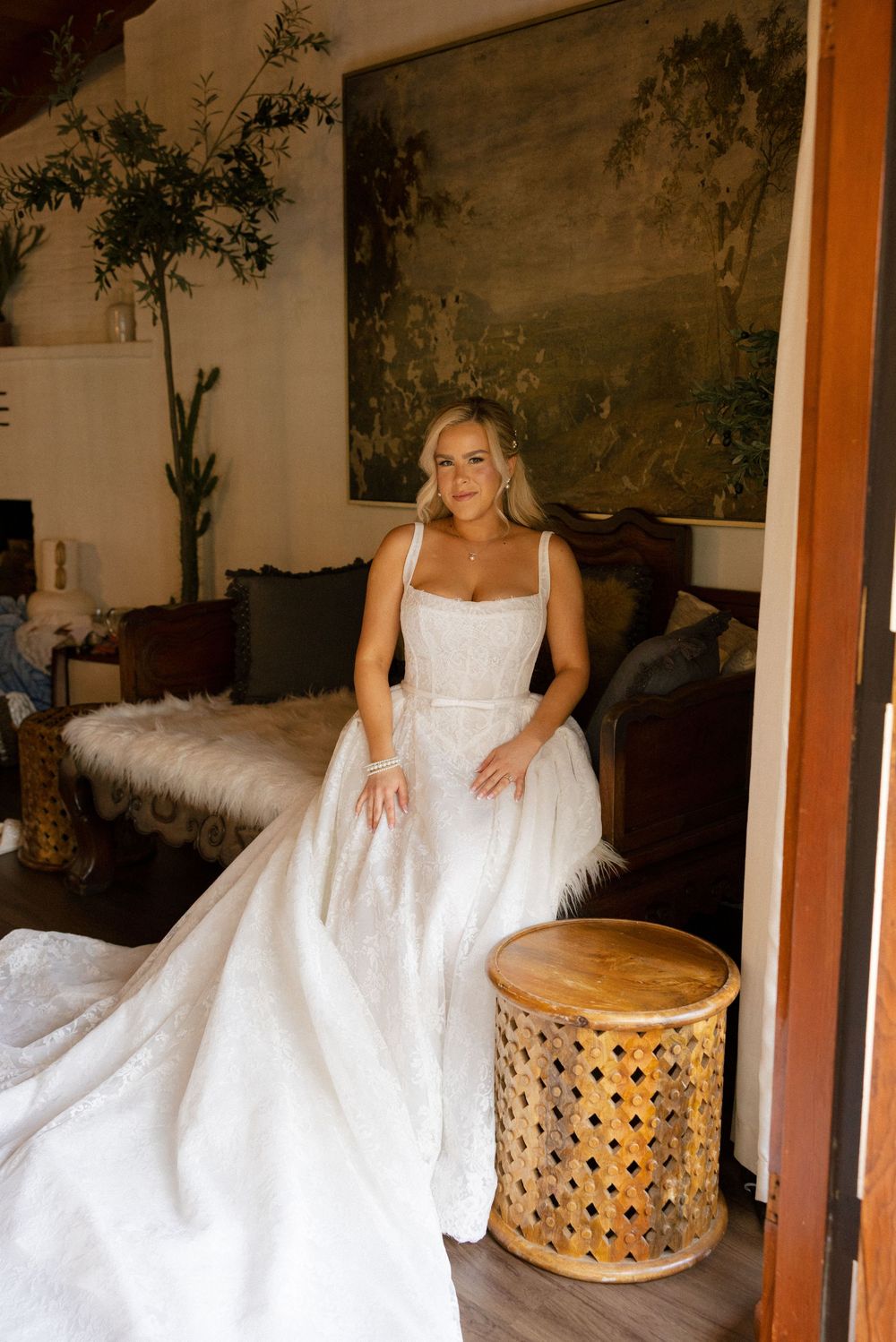 Elegant bride in fitted square-neck ball gown wedding dress poses in rustic boho interior setting.