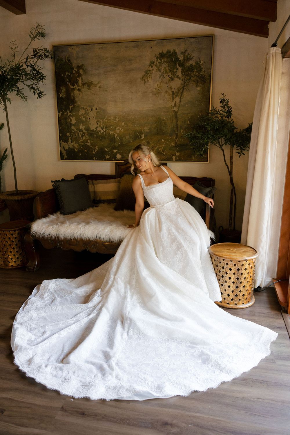 Bride twirling in a voluminous white lace ballgown with a dramatic train in a cozy interior setting.