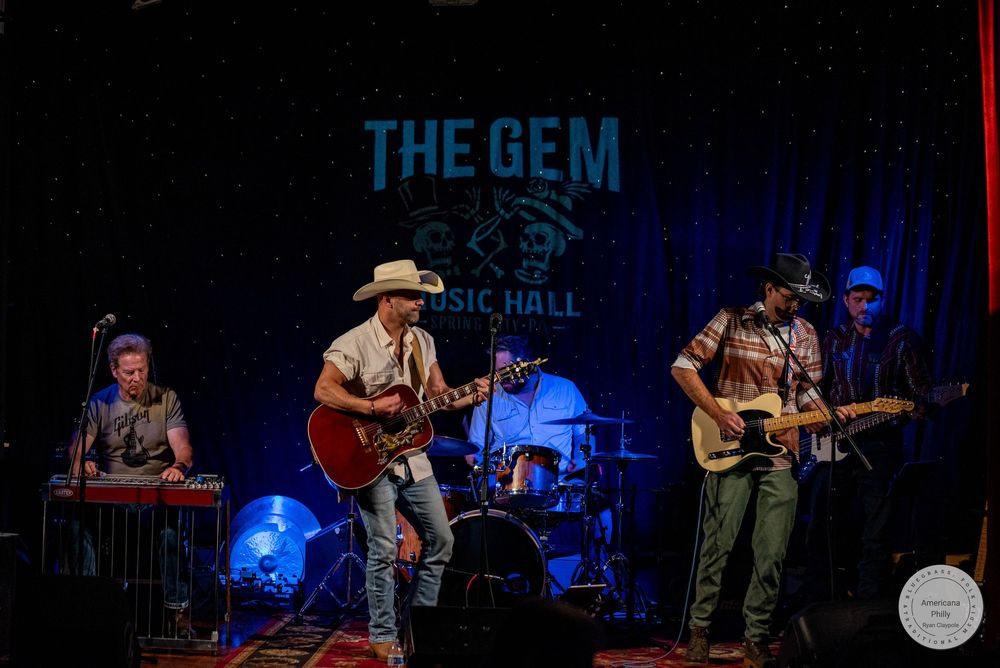 Country band performs live at The Gem Music Hall, featuring guitarist in cowboy hat, keyboardist, drummer, and rhythm guitarist on stage.