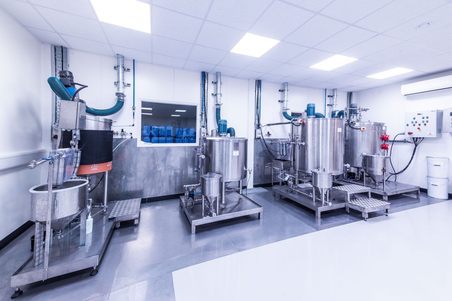 Stainless steel pharmaceutical mixing tanks and processing equipment in a clean, bright industrial laboratory and factory