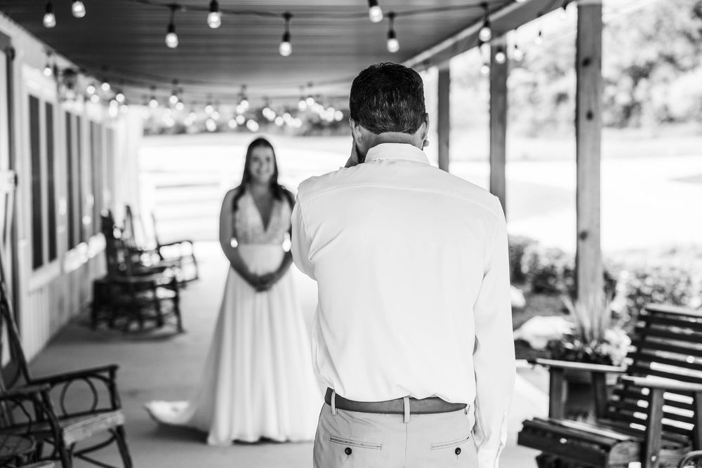 Black and white photo of a groom seeing his bride for the first time on a porch during a wedding first look.