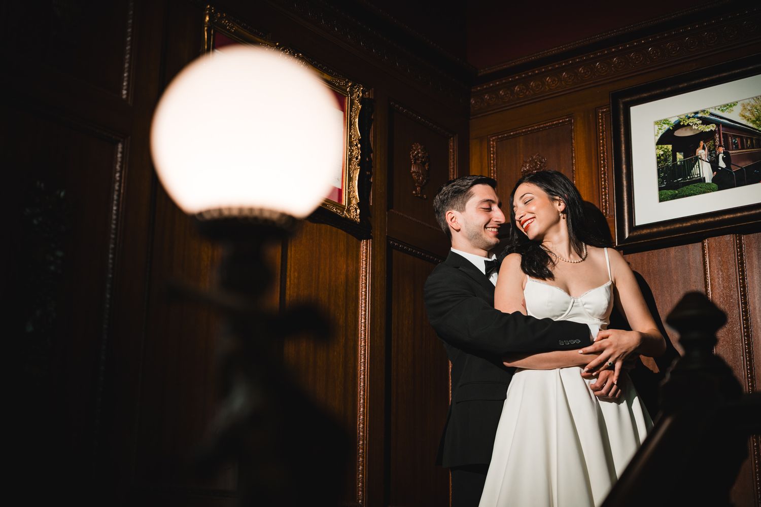 Bride and groom share a romantic moment in a warmly lit wooden interior at their wedding reception.