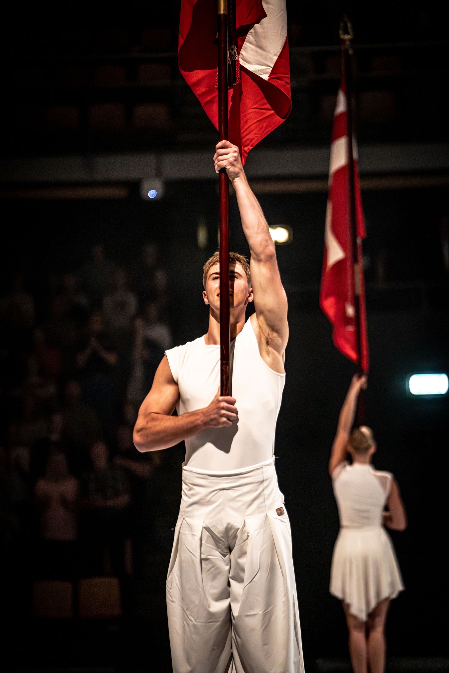 Male dancers in white costumes perform a synchronized contemporary dance routine on a dramatic stage.