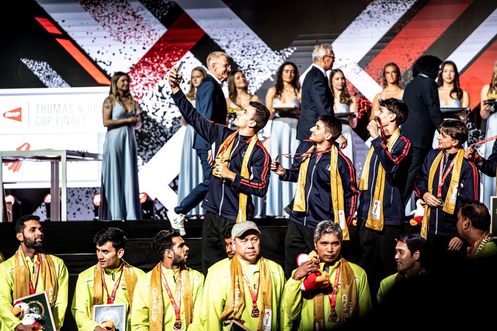 Team celebrates with selfie on stage at badminton world championship awards ceremony.