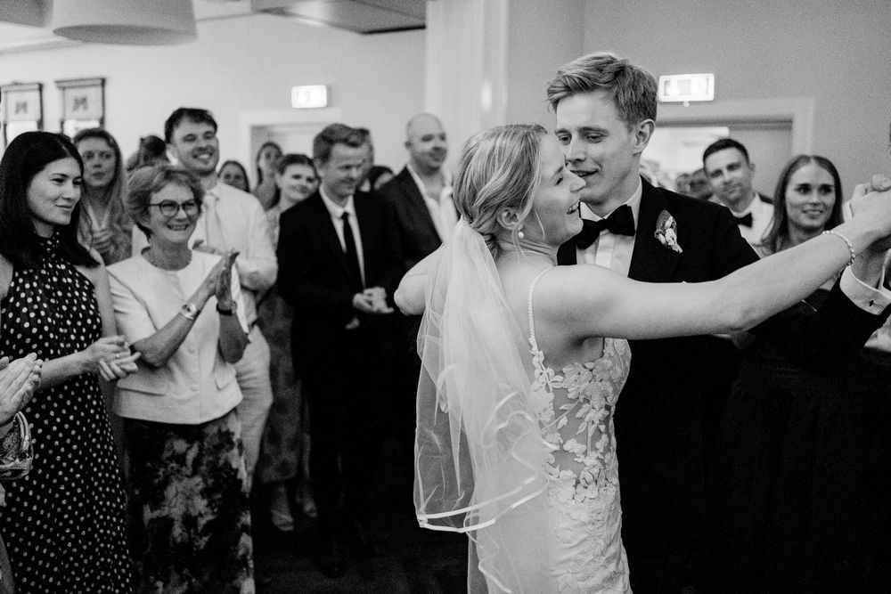 Bride and groom share their first dance surrounded by cheering guests at their wedding reception.
