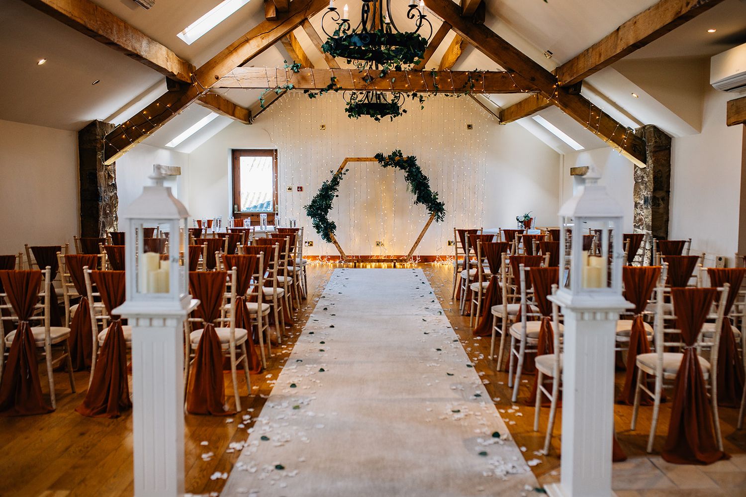 The beeston manor venue prepared with wooden beams, and a white aisle runner for a lancashire wedding photography shoot
