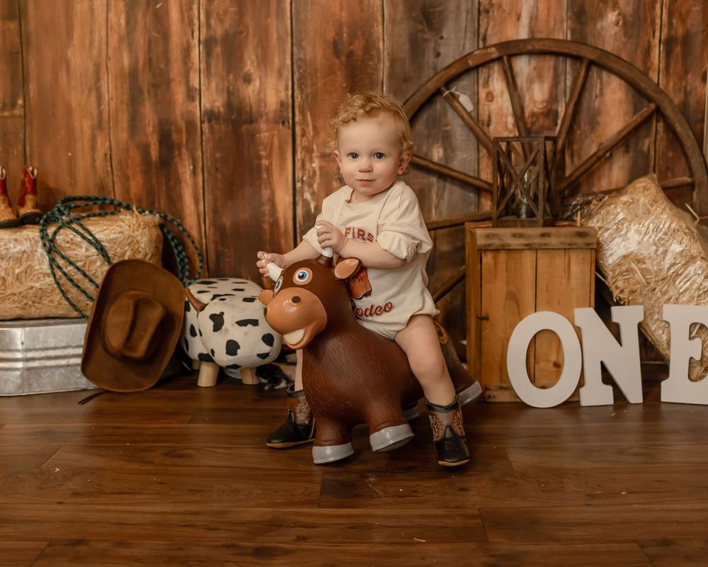 Rustic wood panel backdrop with vintage toys and decorations arranged in a cozy first birthday photoshoot setup.
