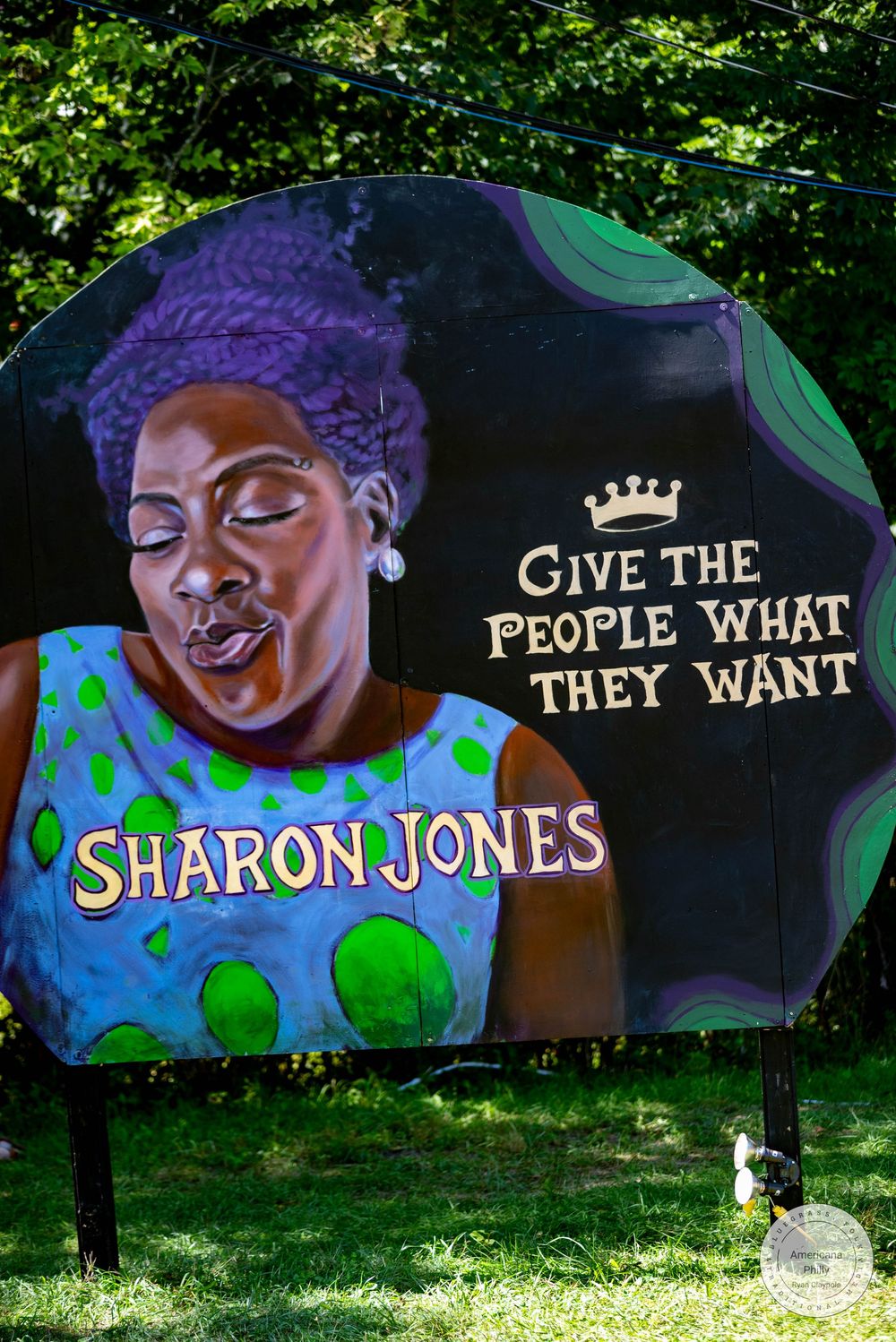 Colorful mural of Sharon Jones with purple hair and the quote Give The People What They Want on a dark background.