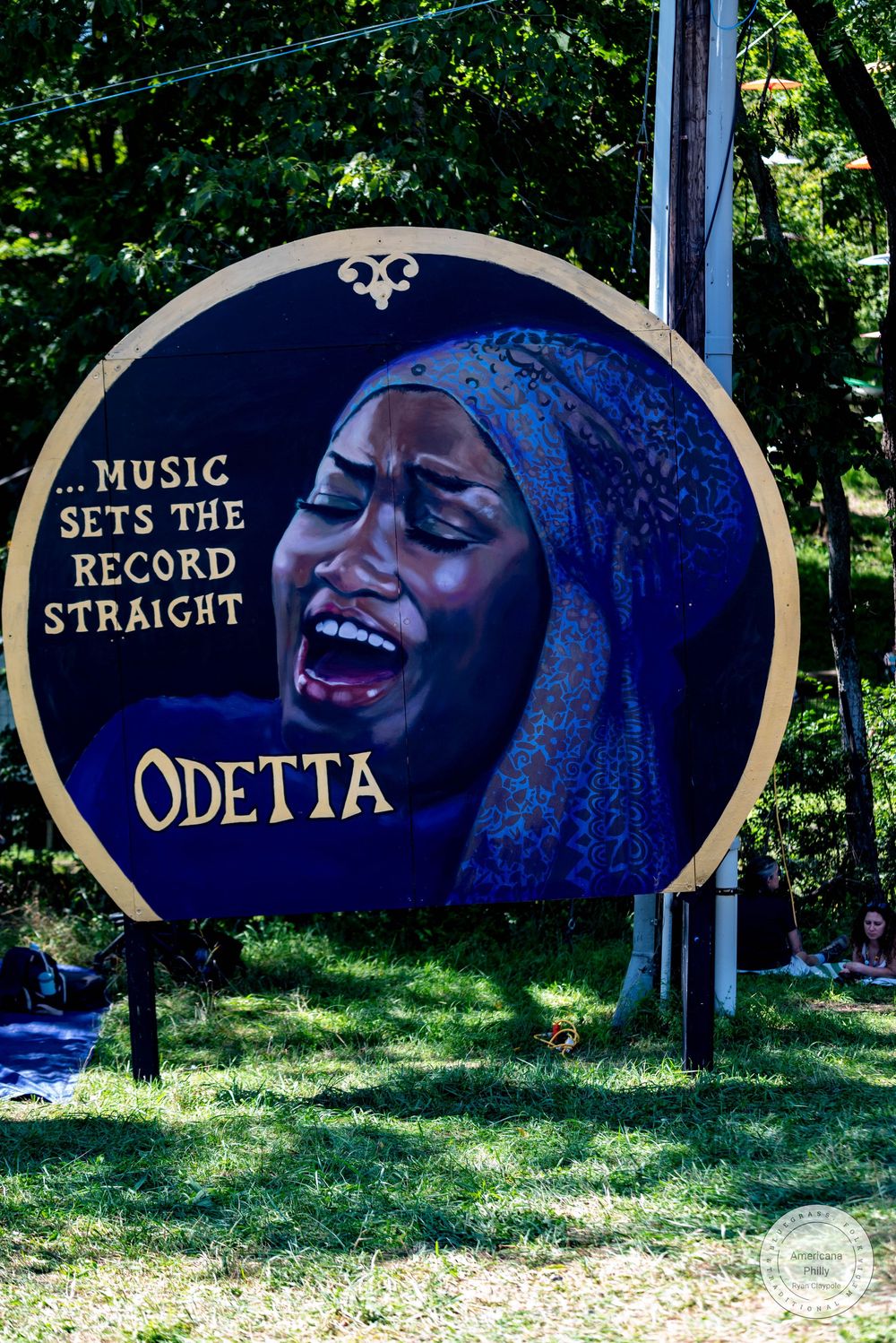 Circular mural of folk singer Odetta with quote Music Sets The Record Straight painted on dark background outdoors.