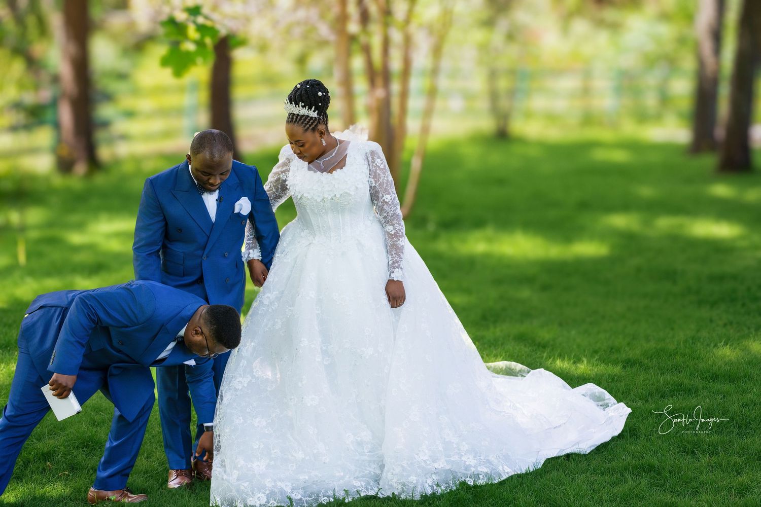Bride in white ball gown with groom in blue suit during outdoor wedding photo session on green lawn.