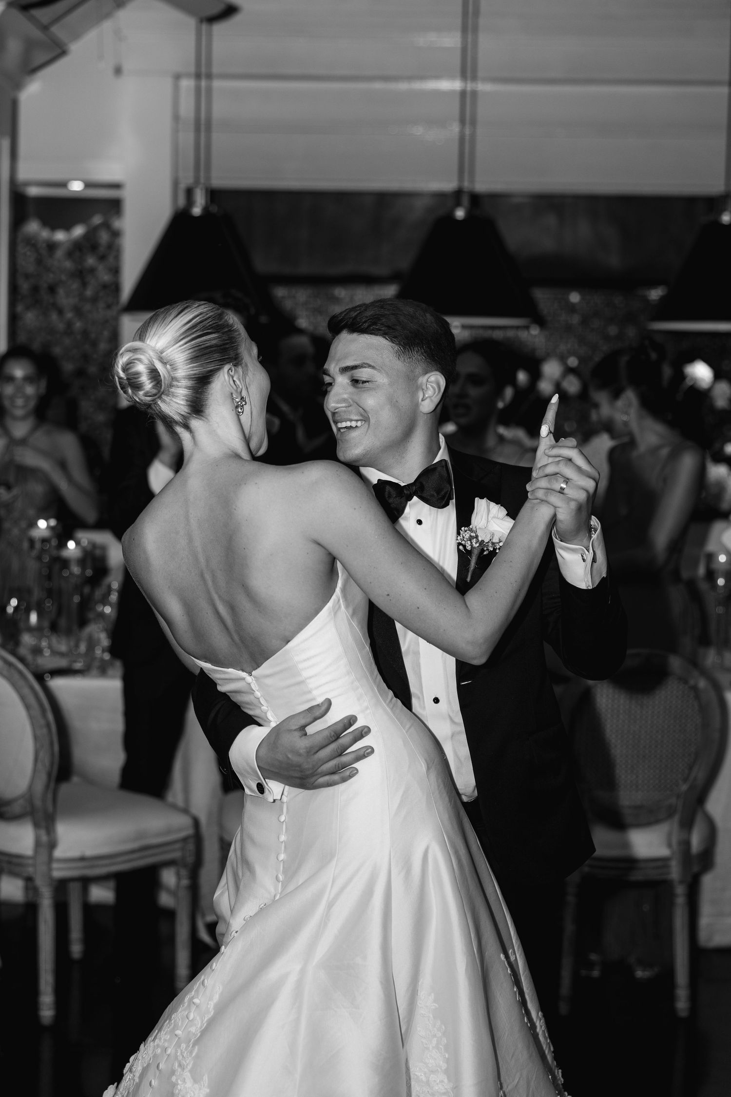Couple sharing a romantic kiss at a formal event, woman in white sequin gown and man in black tuxedo.