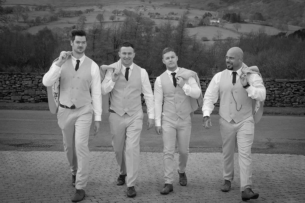 Four groomsmen in matching light suits walk confidently together at New House Farm wedding venue
