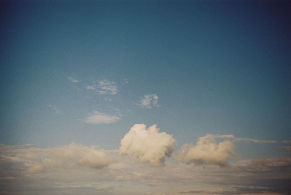 Blue sky with fluffy white cumulus clouds floating peacefully on a sunny day.