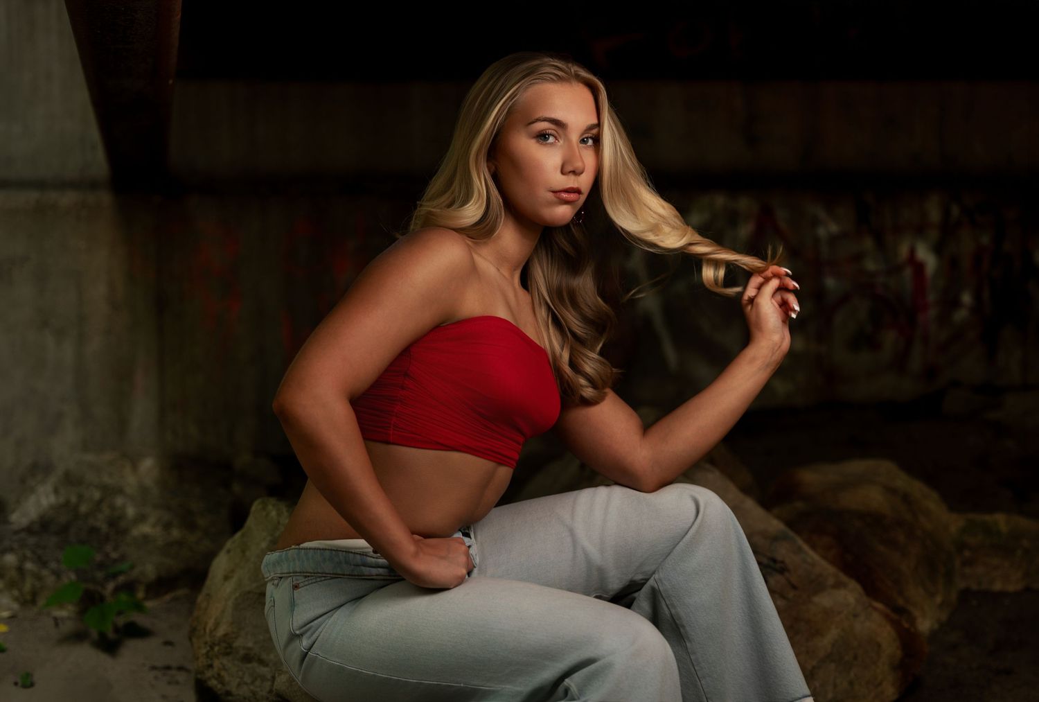 Senior portrait of a blonde girl in a red top photographed in a rustic setting