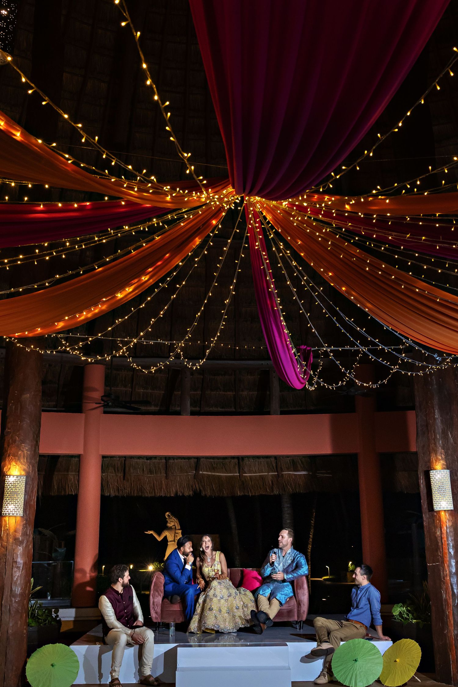 Guests performing Bhangra dance at an Indian wedding reception on a wooden dance floor.
