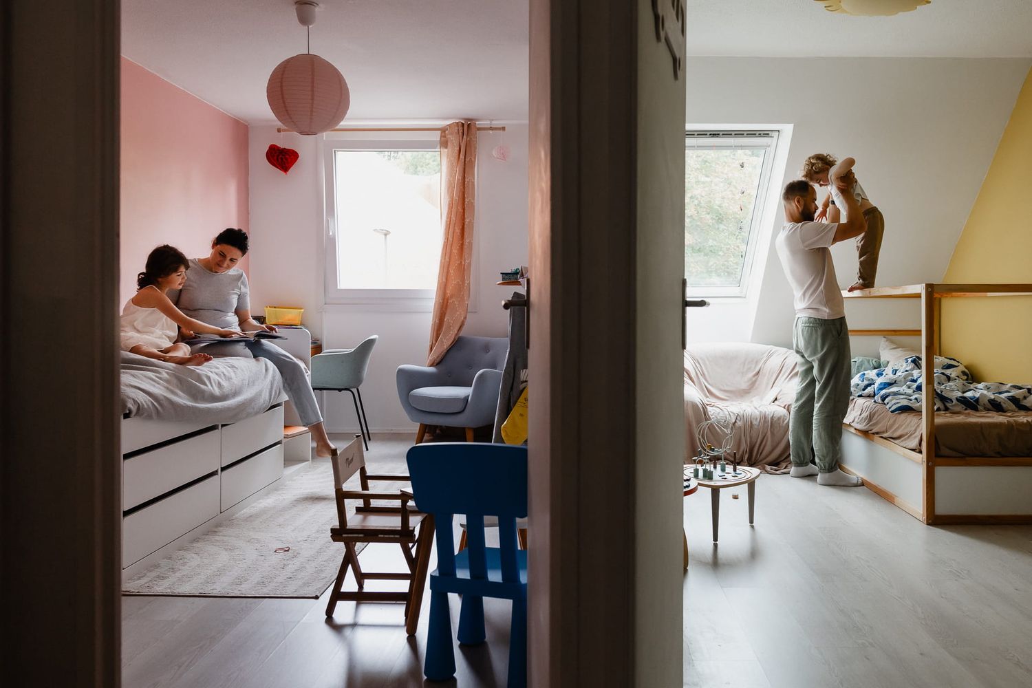 Photographe famille a Lille, la grande blottie avec sa maman dans son lit et le petit qui escalade le sien avec son papa