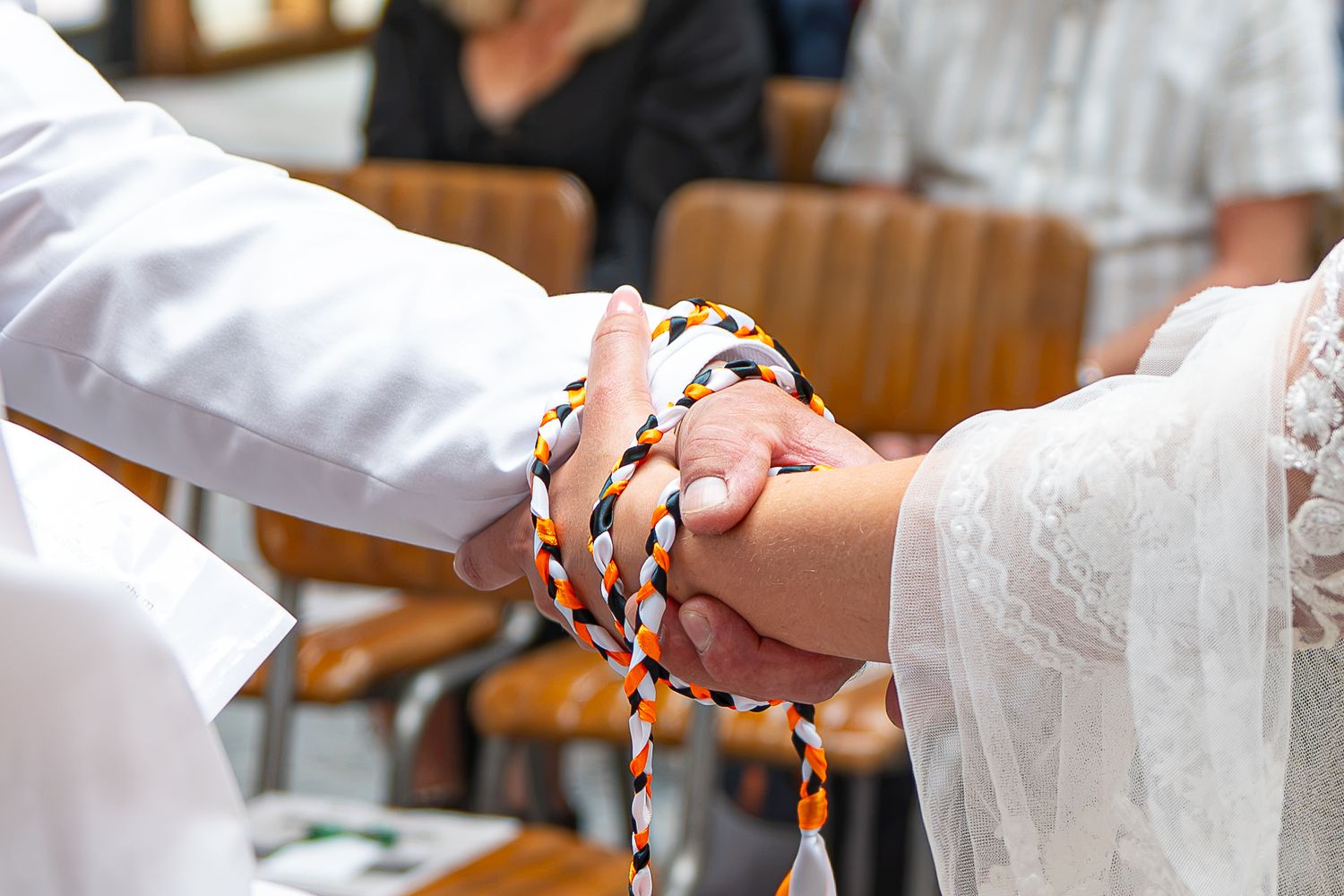 Couple's hands bound together with colorful braided cord during a traditional handfasting wedding ceremony.Yorkshire, Sheffield, UK