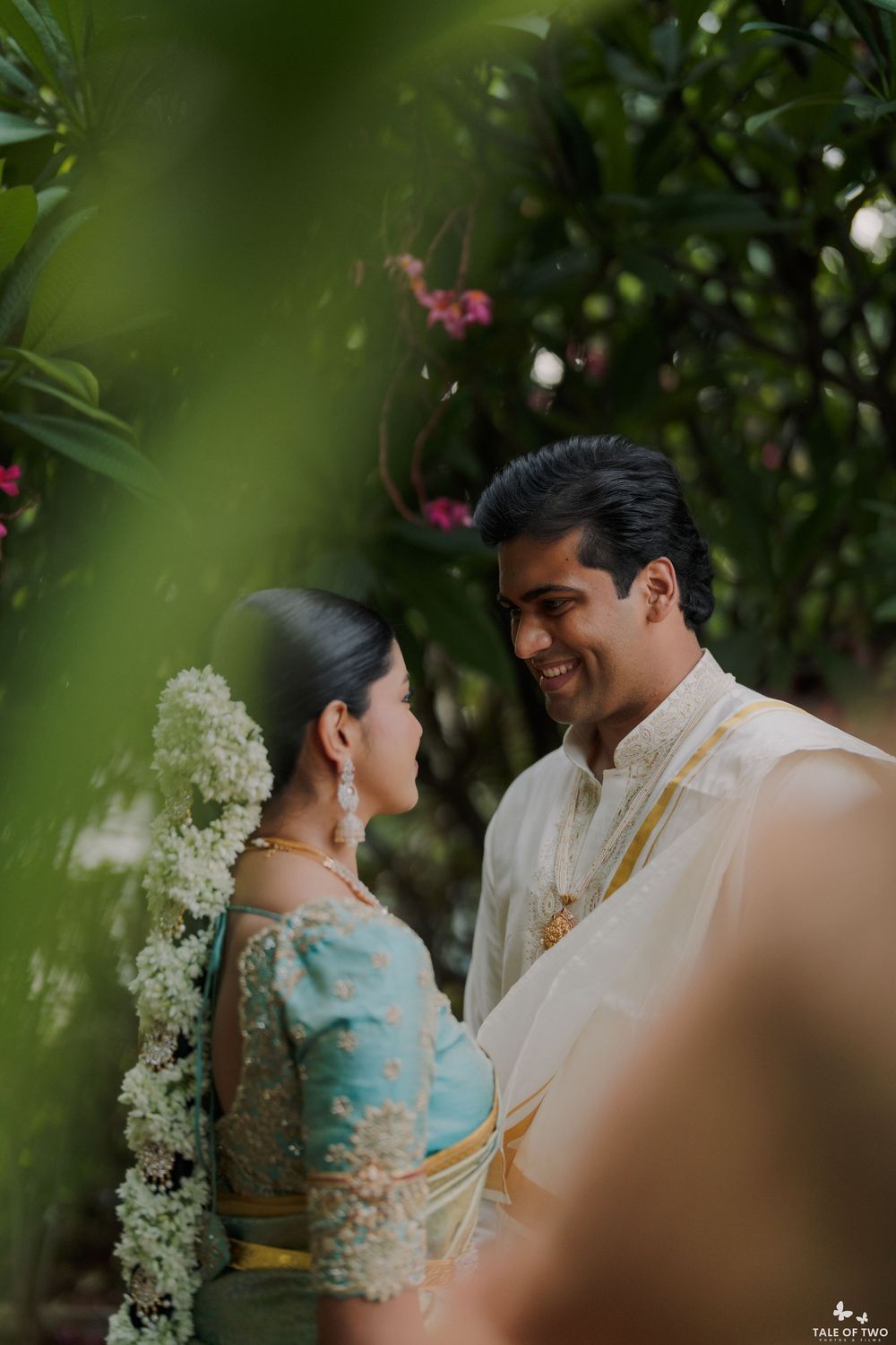 South Indian bride and groom share a romantic moment surrounded by lush greenery during their traditional wedding ceremony.