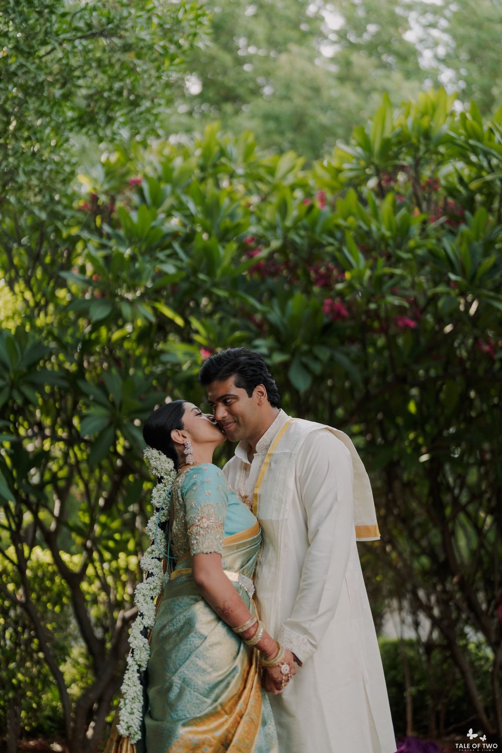 Indian couple in traditional attire sharing a romantic moment in a lush garden during their South Indian wedding ceremony.