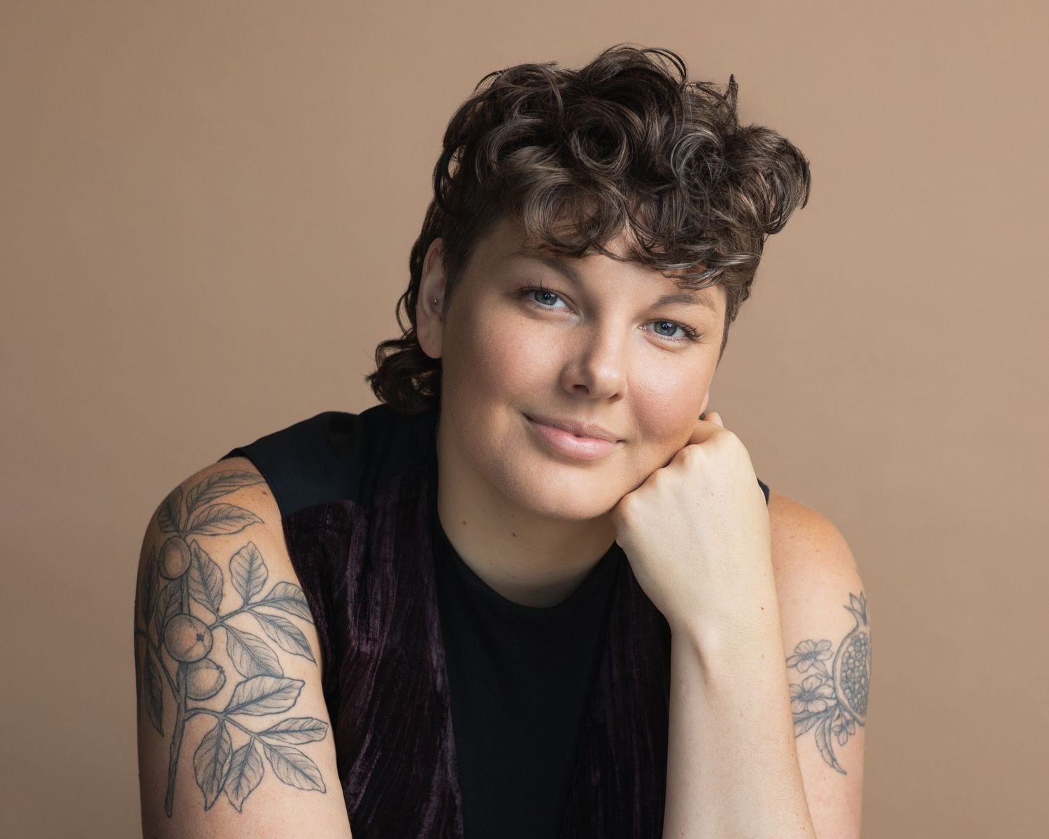 Creative actor headshot with relaxed expression on warm studio backdrop