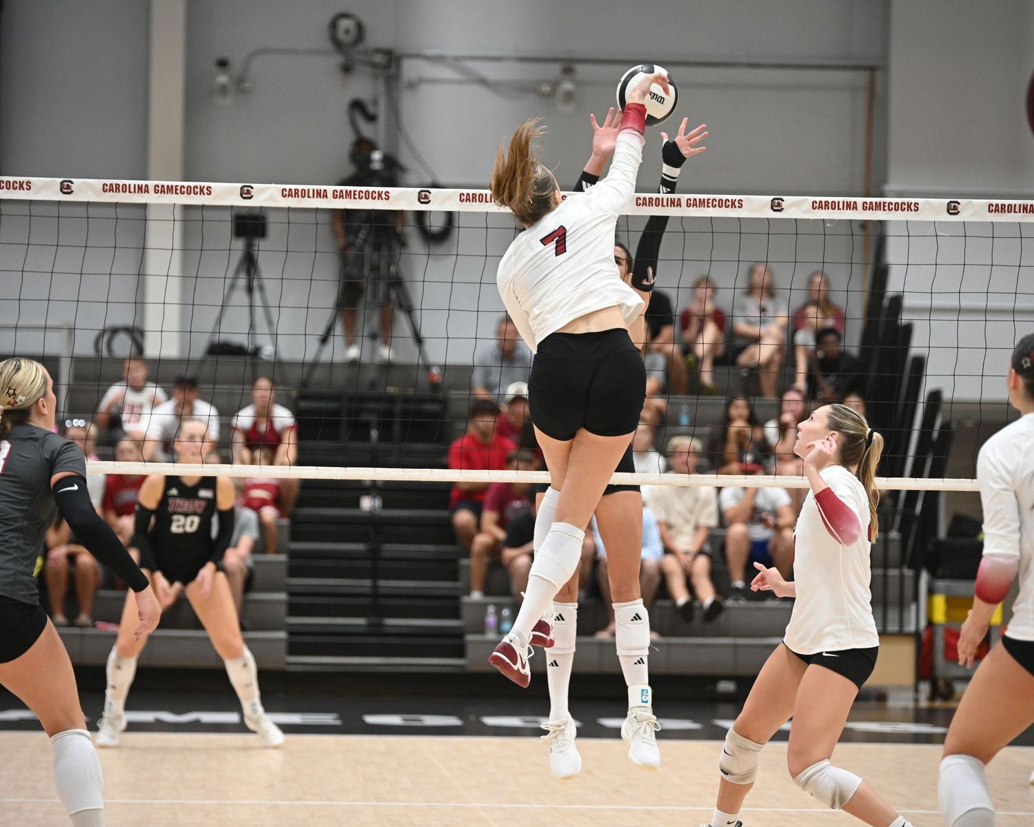 Two South Carolina volleyball players reach above the net to block the ball.