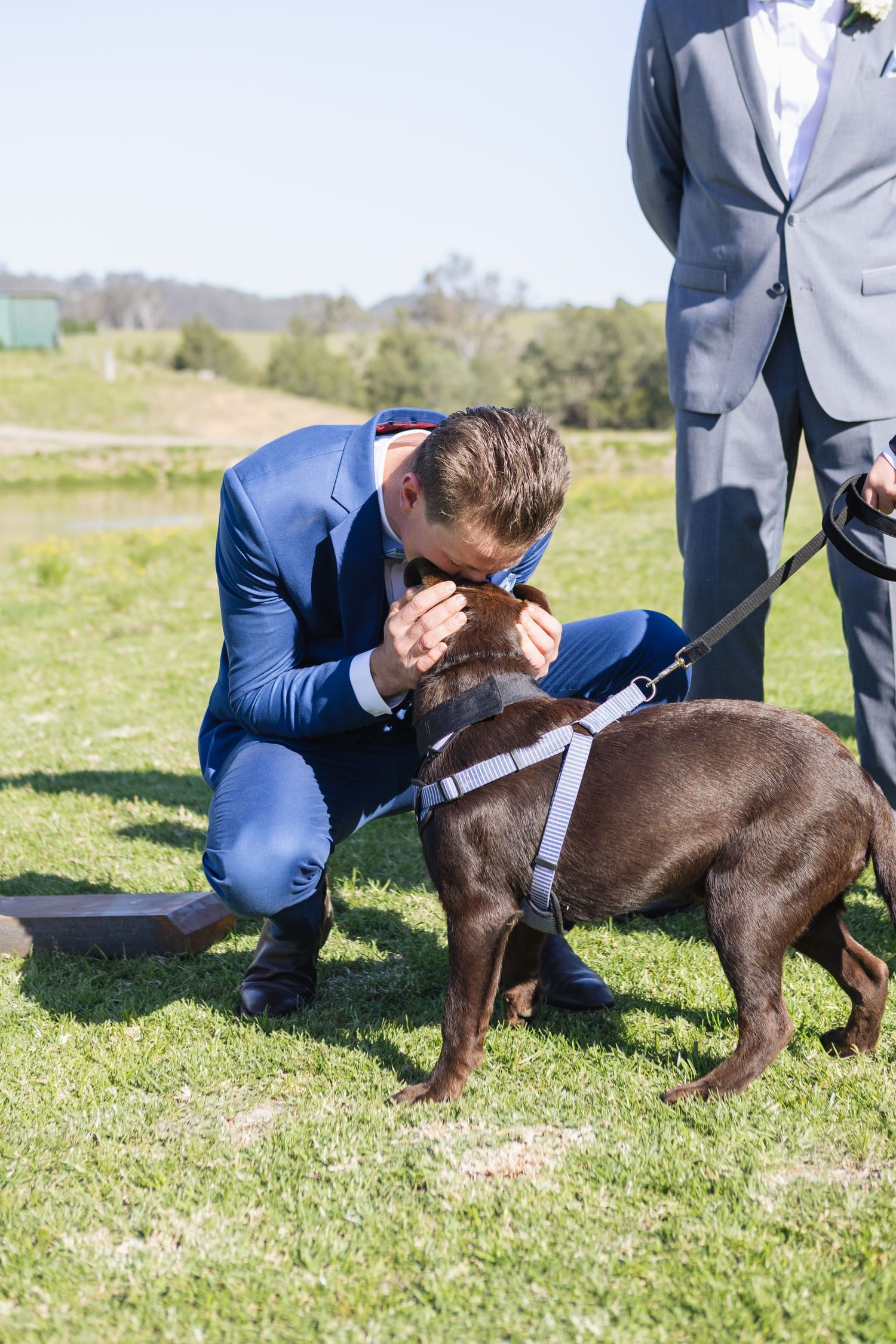 groom hugging dog at Jess and Lachie’s wedding ceremony overlooking the dam at Dungog Weddings