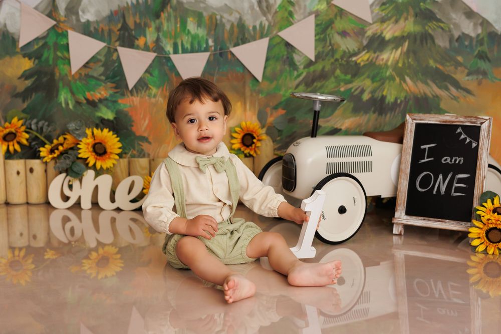 First birthday setup with rustic backdrop featuring sunflowers, bunting and vintage white toy car.