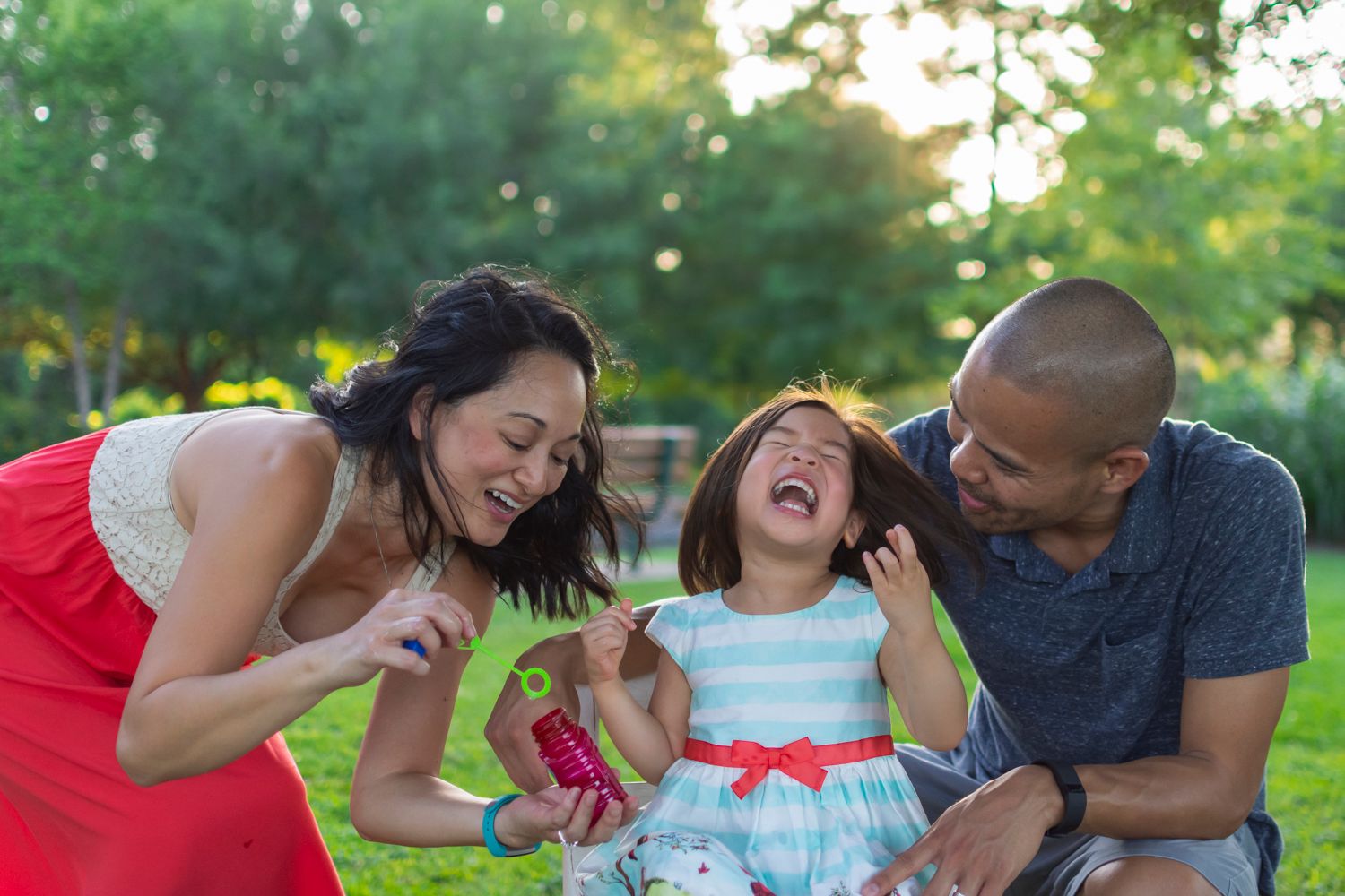 Family of three blowing bubbles in Sugar Land, TX, candid and playful.