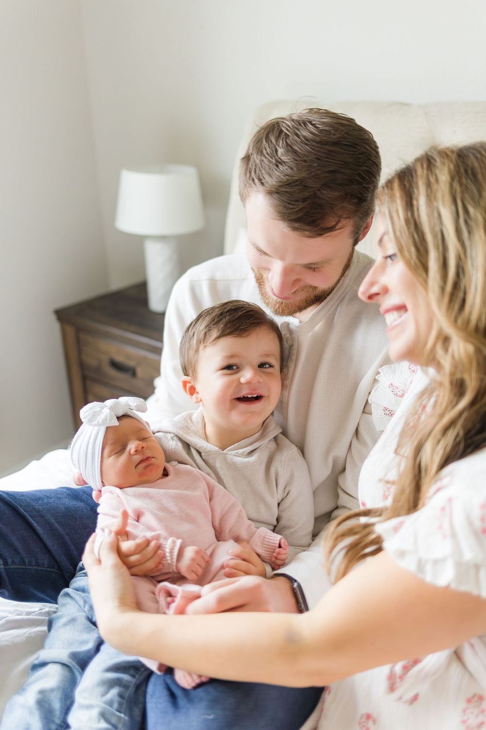Mother and father cuddling their newborn baby together during a warm, natural indoor family photography session.