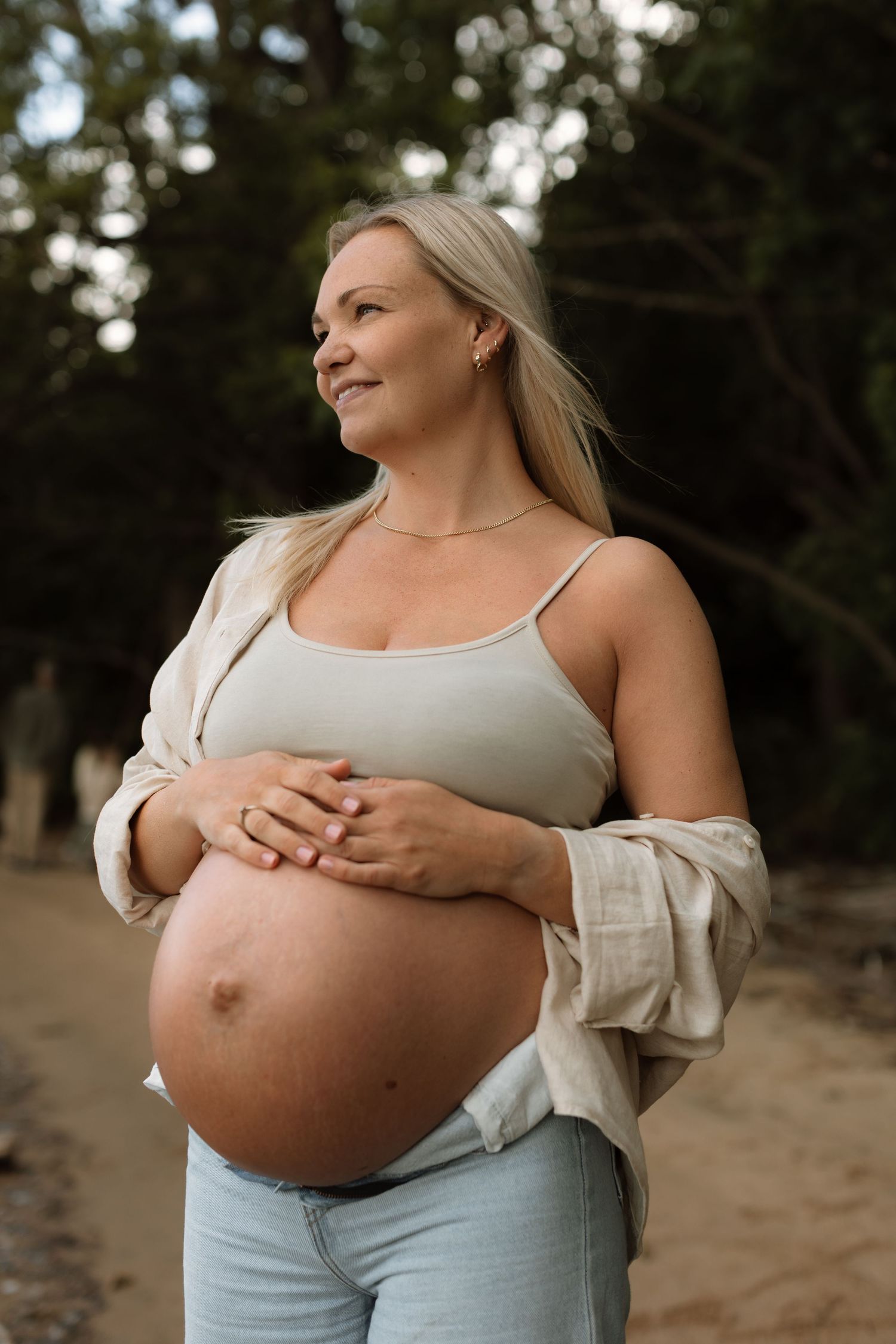 Gravid dame i solnedgang på stranden i naturlige klær