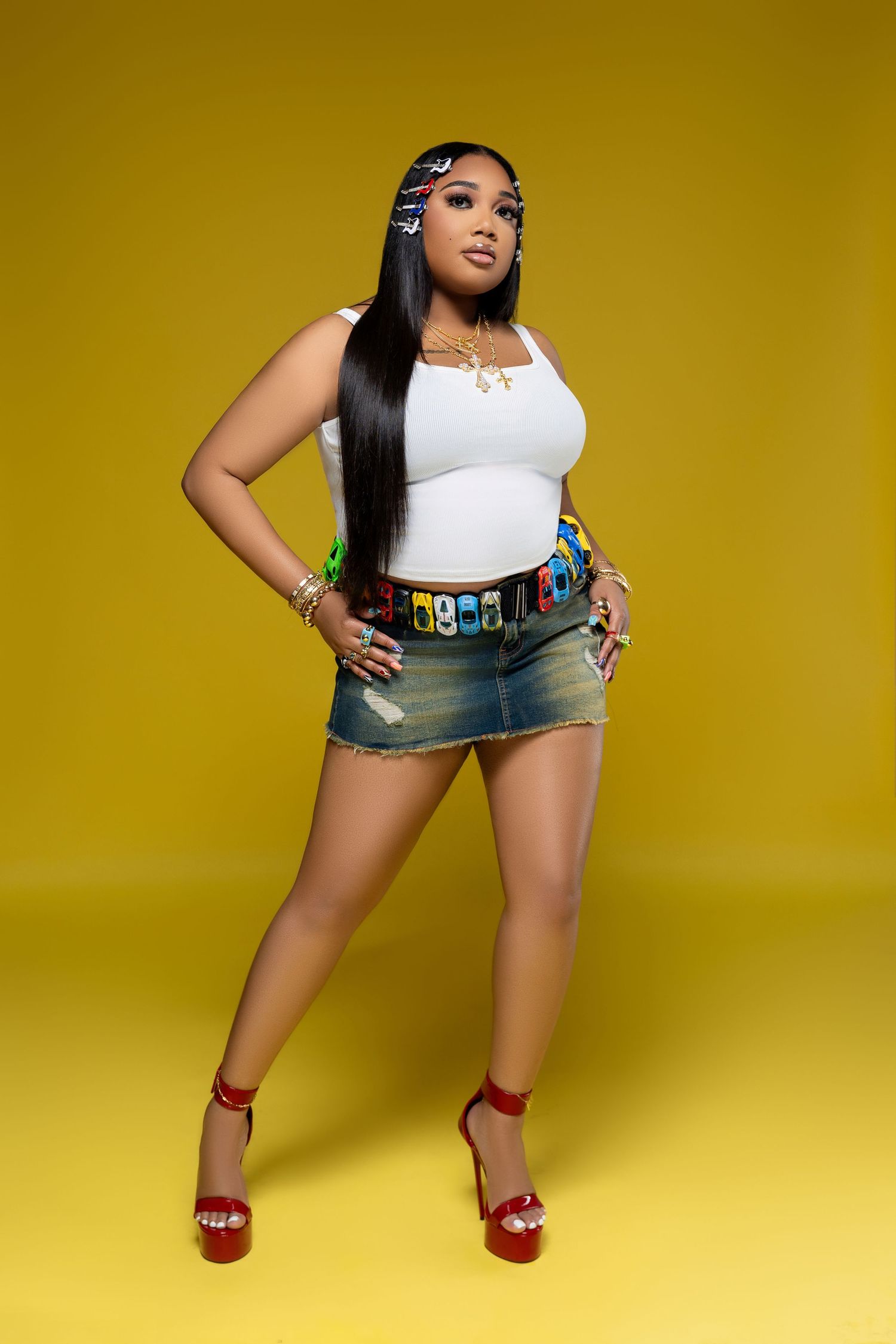 Fashion portrait against yellow backdrop featuring denim skirt and white top.
