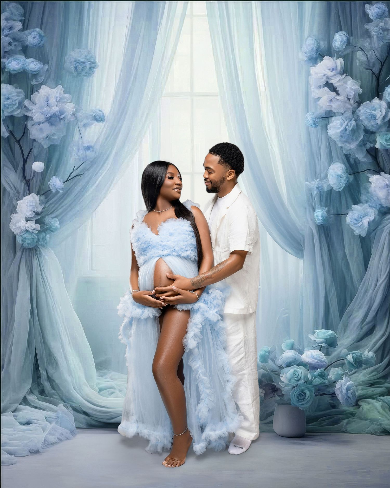 Elegant maternity photo shoot featuring a couple in white against blue floral backdrop and flowing curtains.