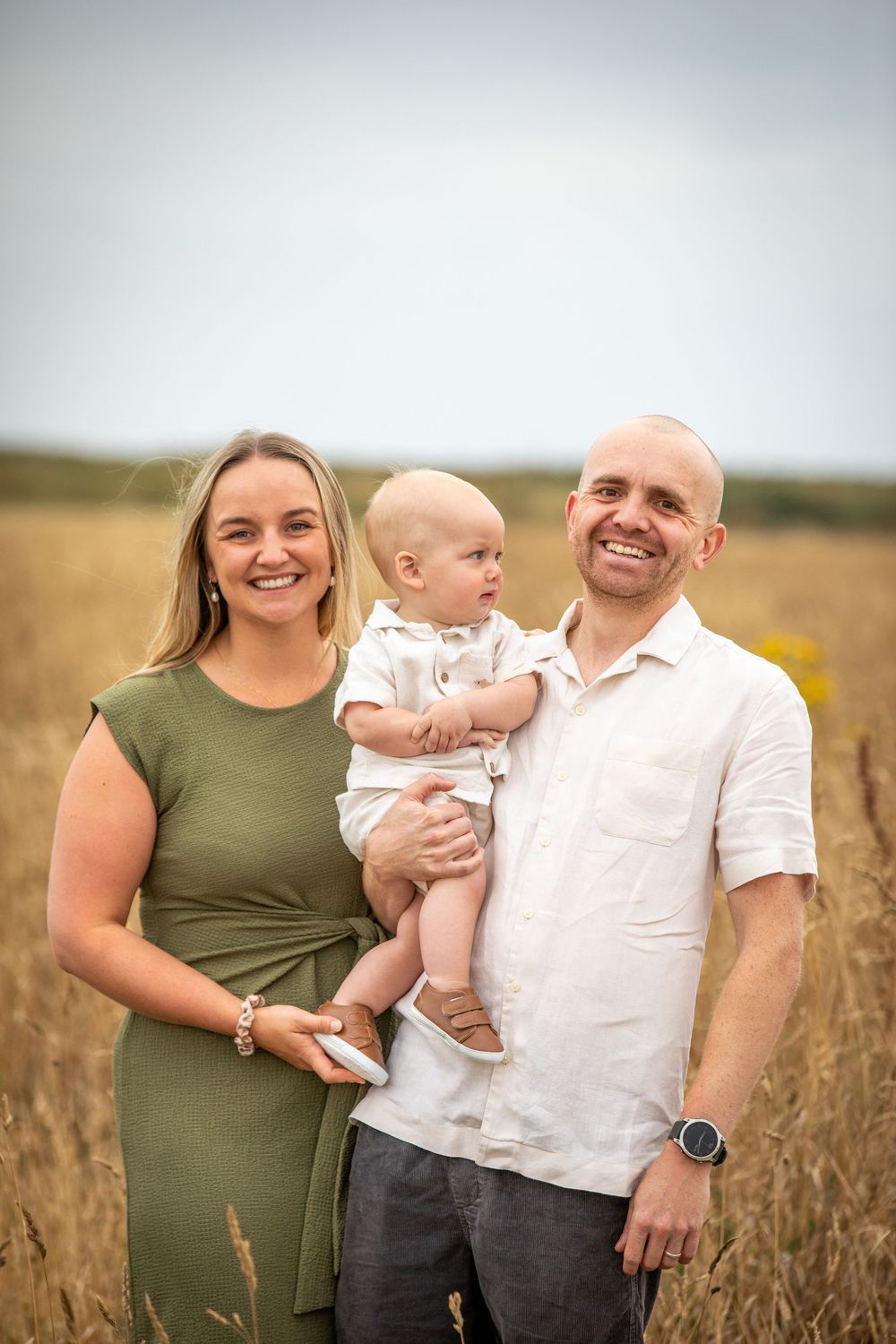 Family portrait in a golden wheat field during sunset.