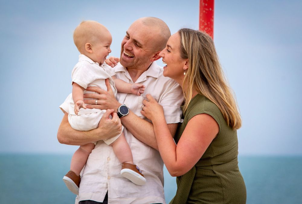 Family shares tender moments against blue sky backdrop.