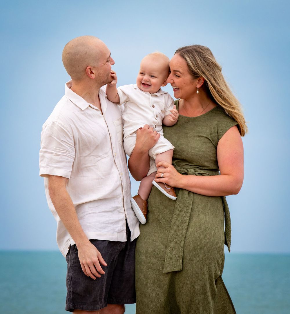 Family embraces while enjoying time together by the ocean.
