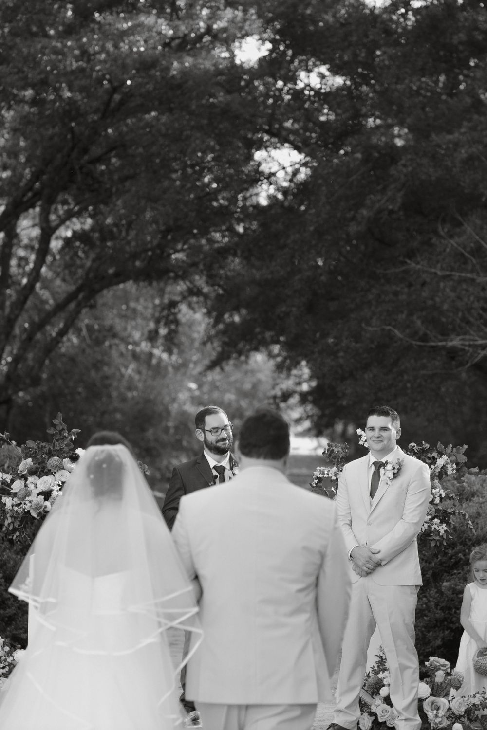 Black and white capture of intimate outdoor wedding ceremony with floral decorations.