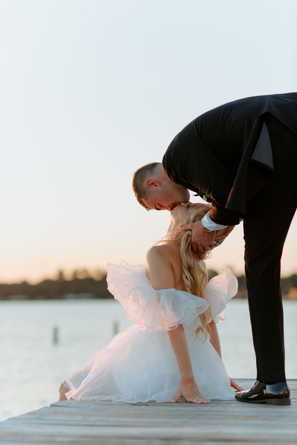 Romantic sunset moment between couple on wooden dock by water.